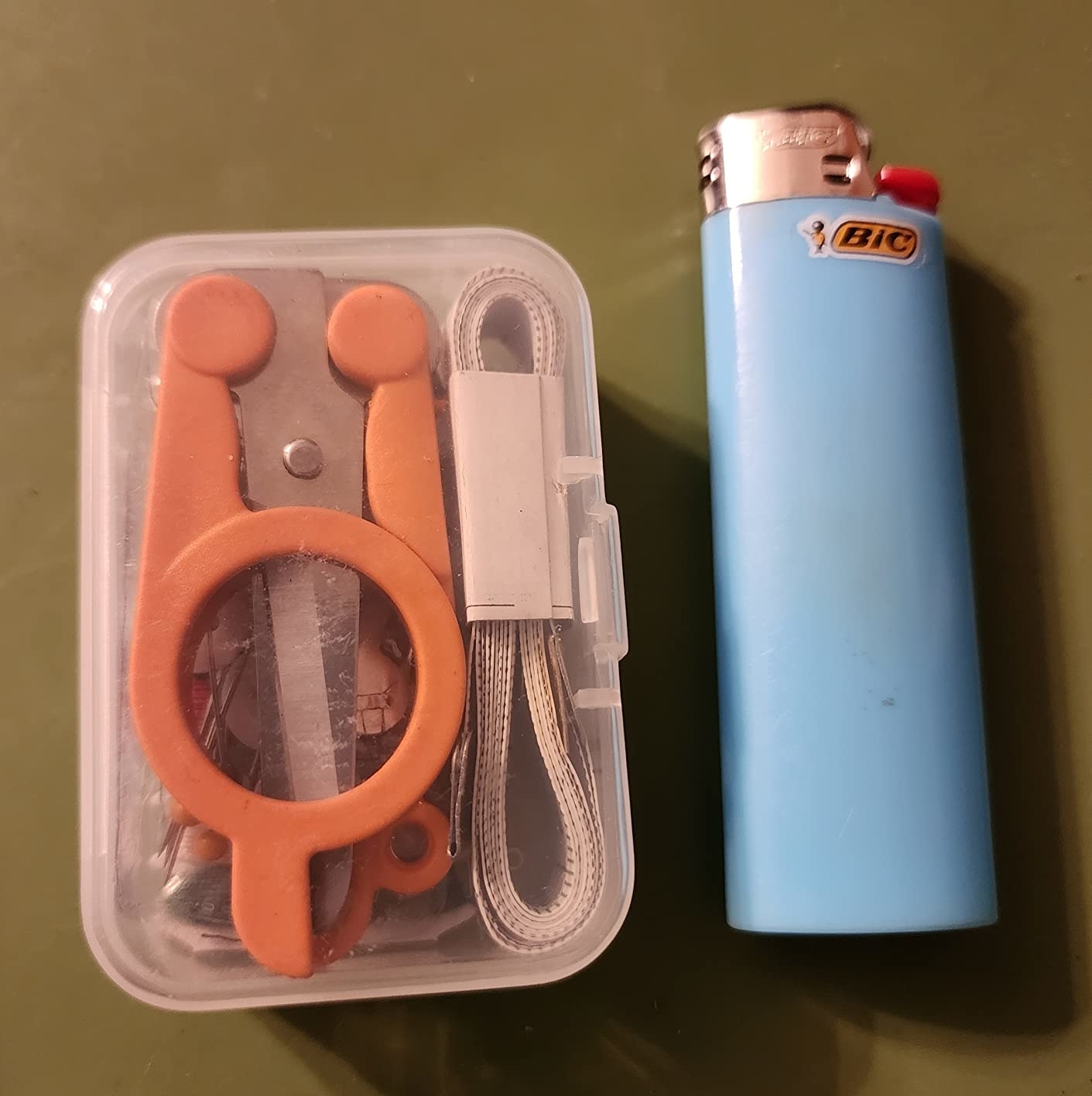 Reviewer&#x27;s photo of the sewing kit next to a Bic lighter for scale