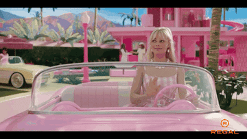 Barbie&#x27;s Margot Robbie smiling in a car and waving