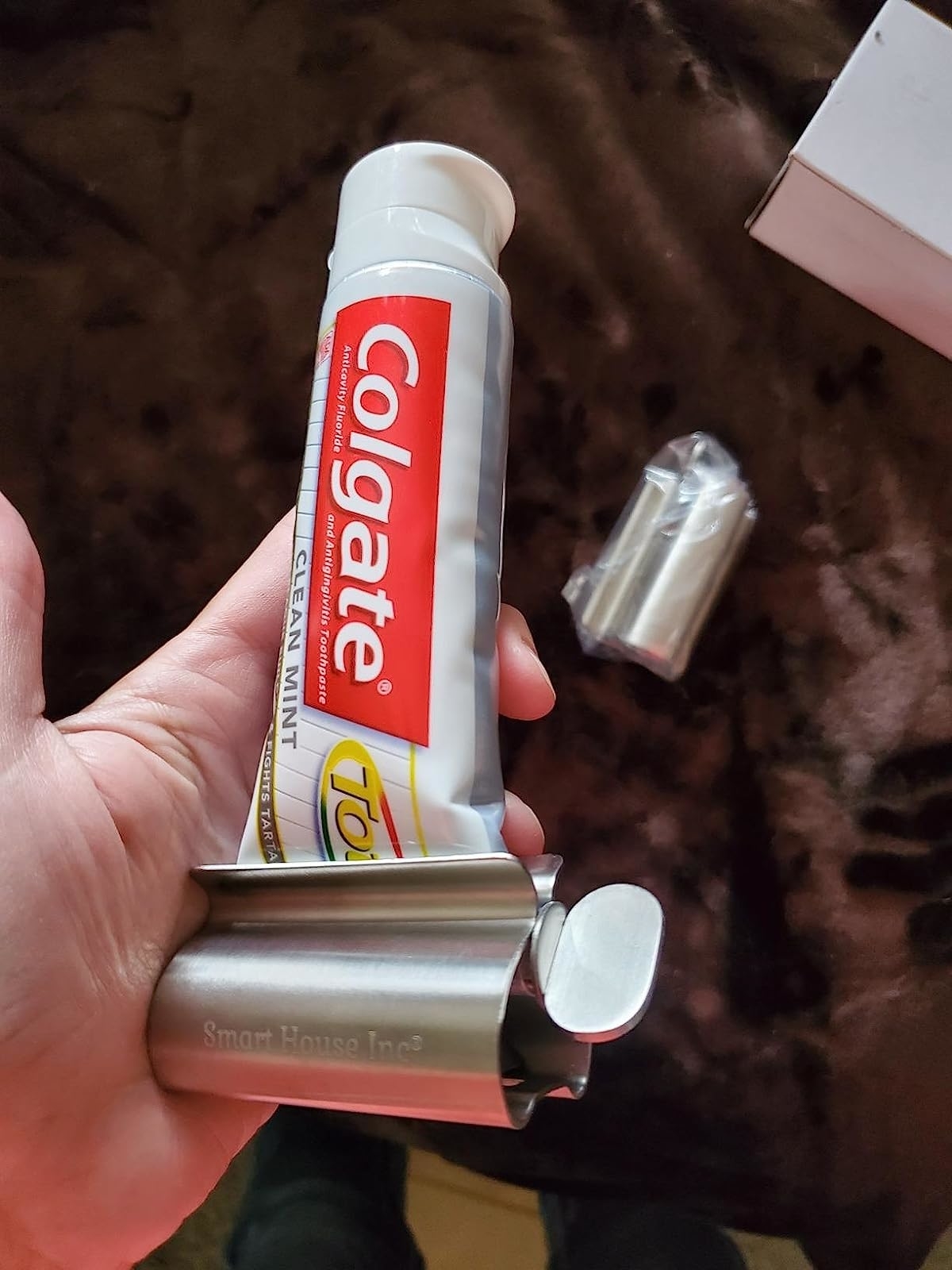 Reviewer holding toothpaste in the metal squeezer