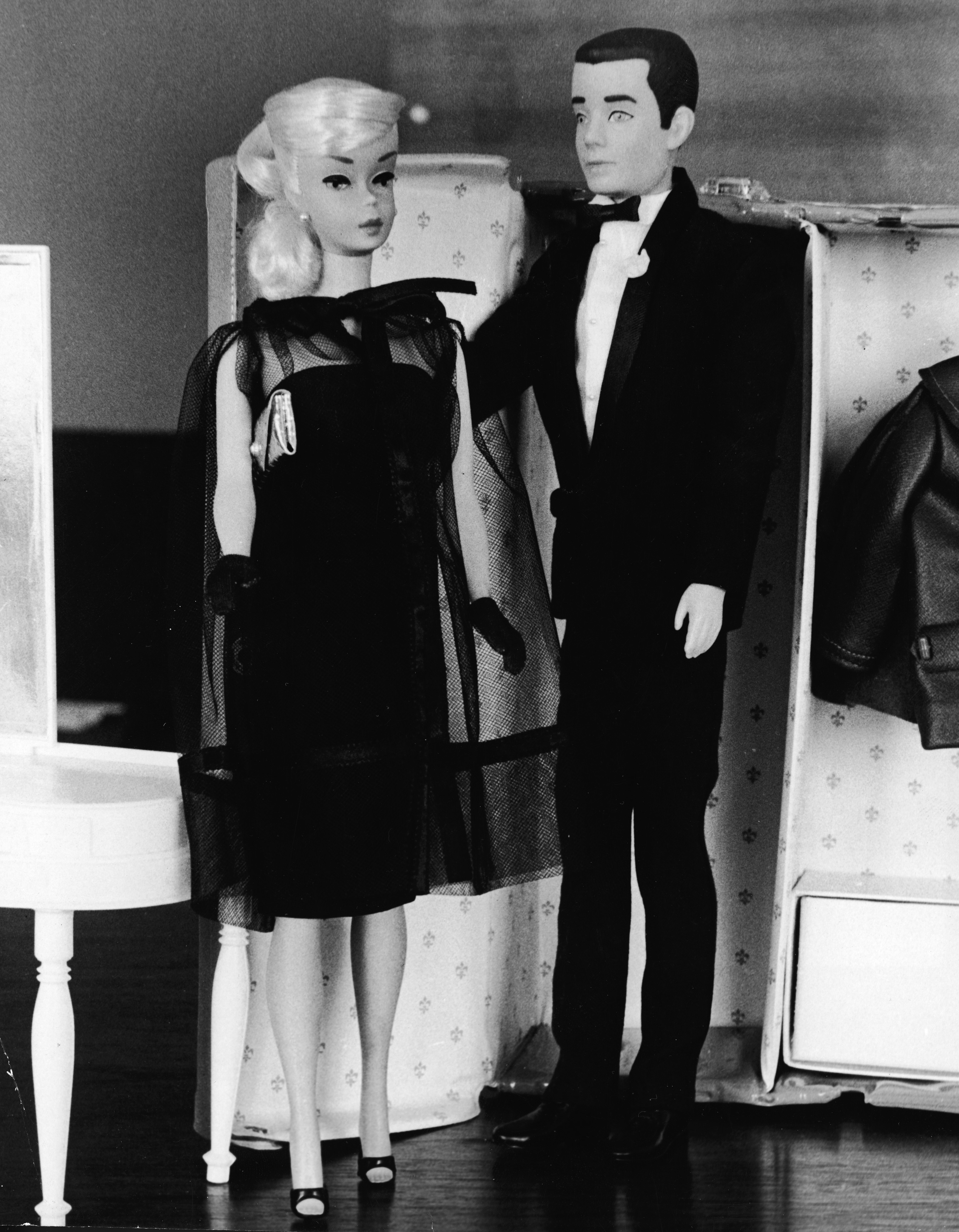 Barbie and Ken, in formal wear, stand together in front of a toy closet, December 15, 1964