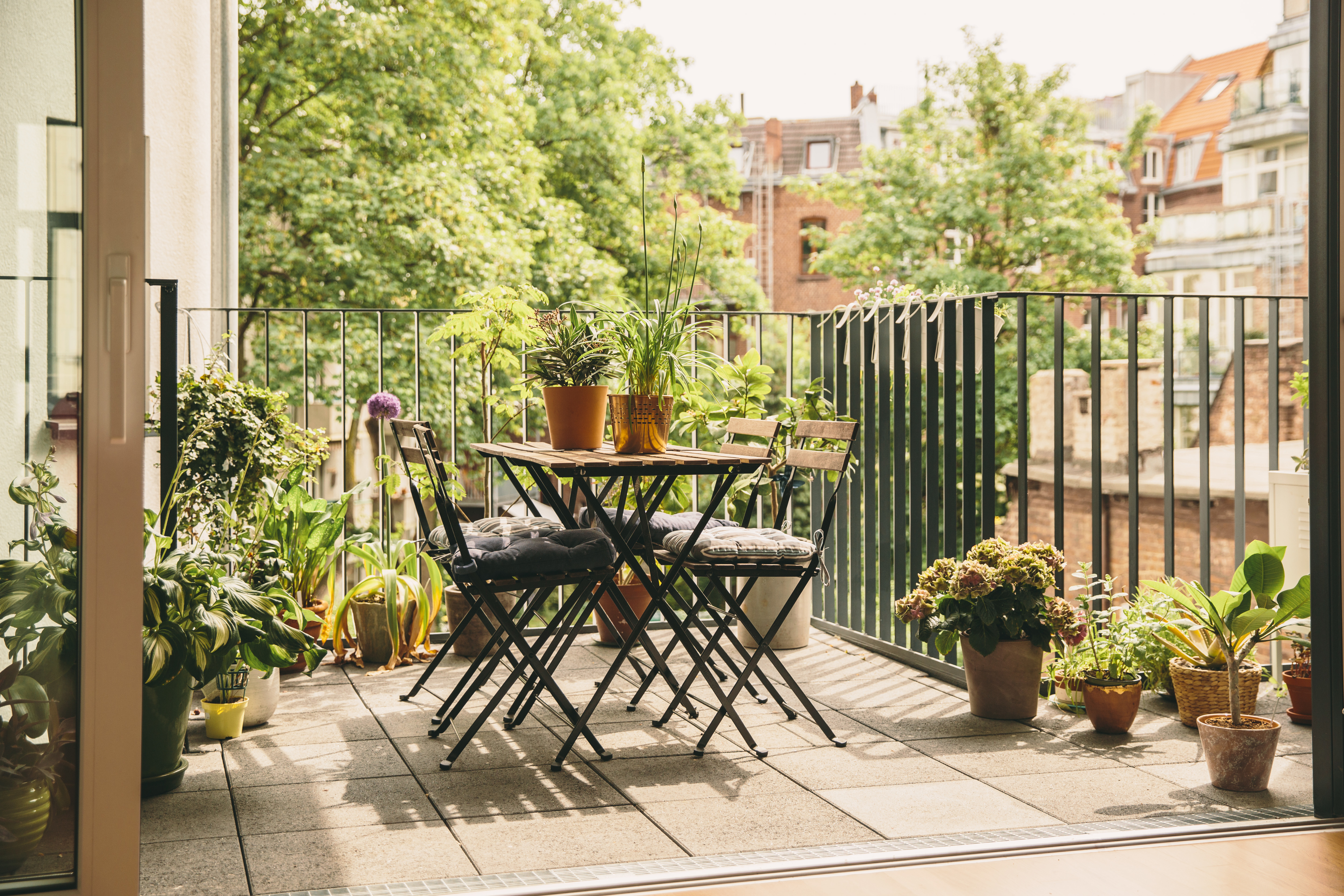 A balcony with a bistro table and lots of plants