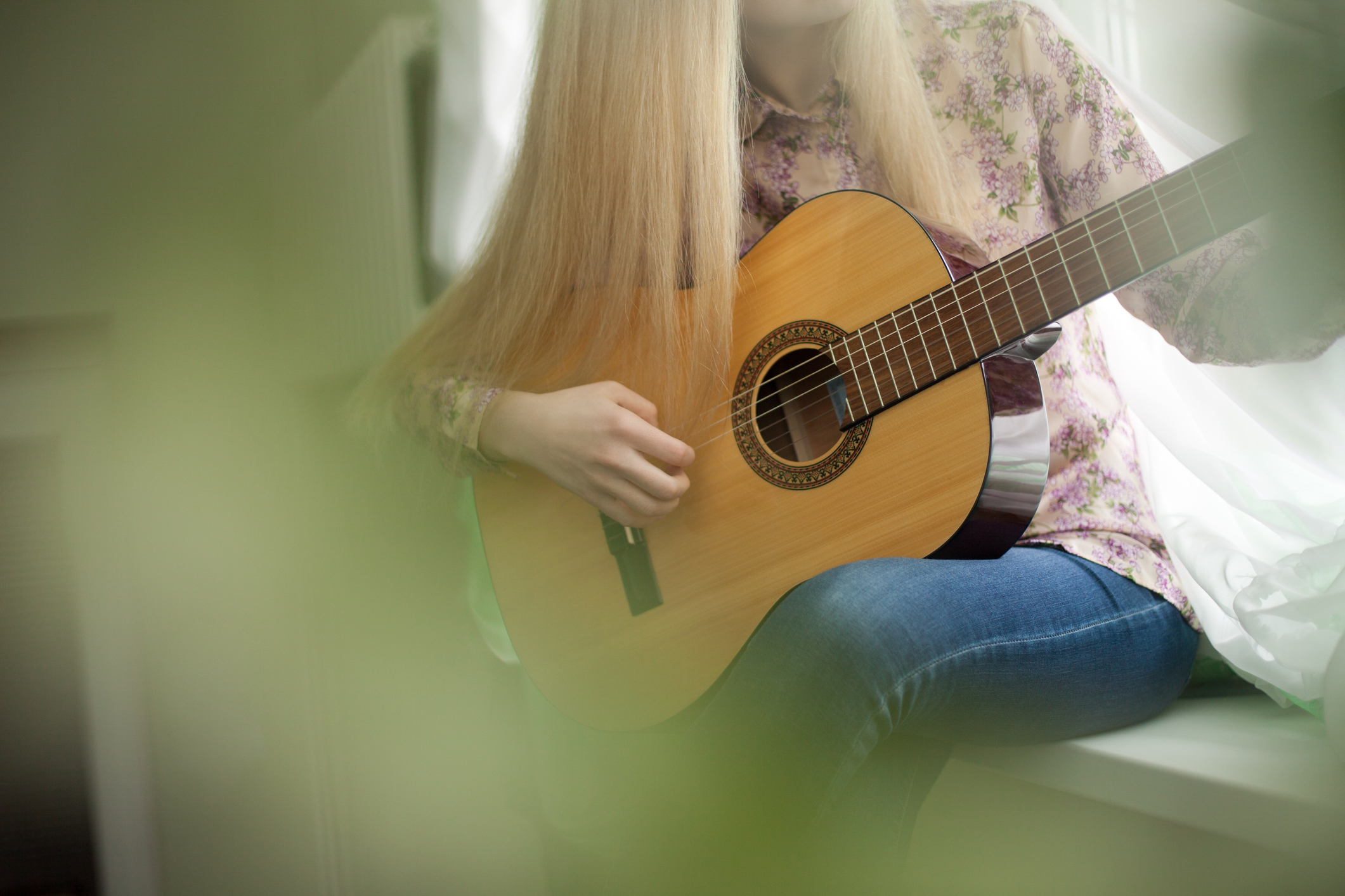 Stock image of woman playing guitar, face cropped out