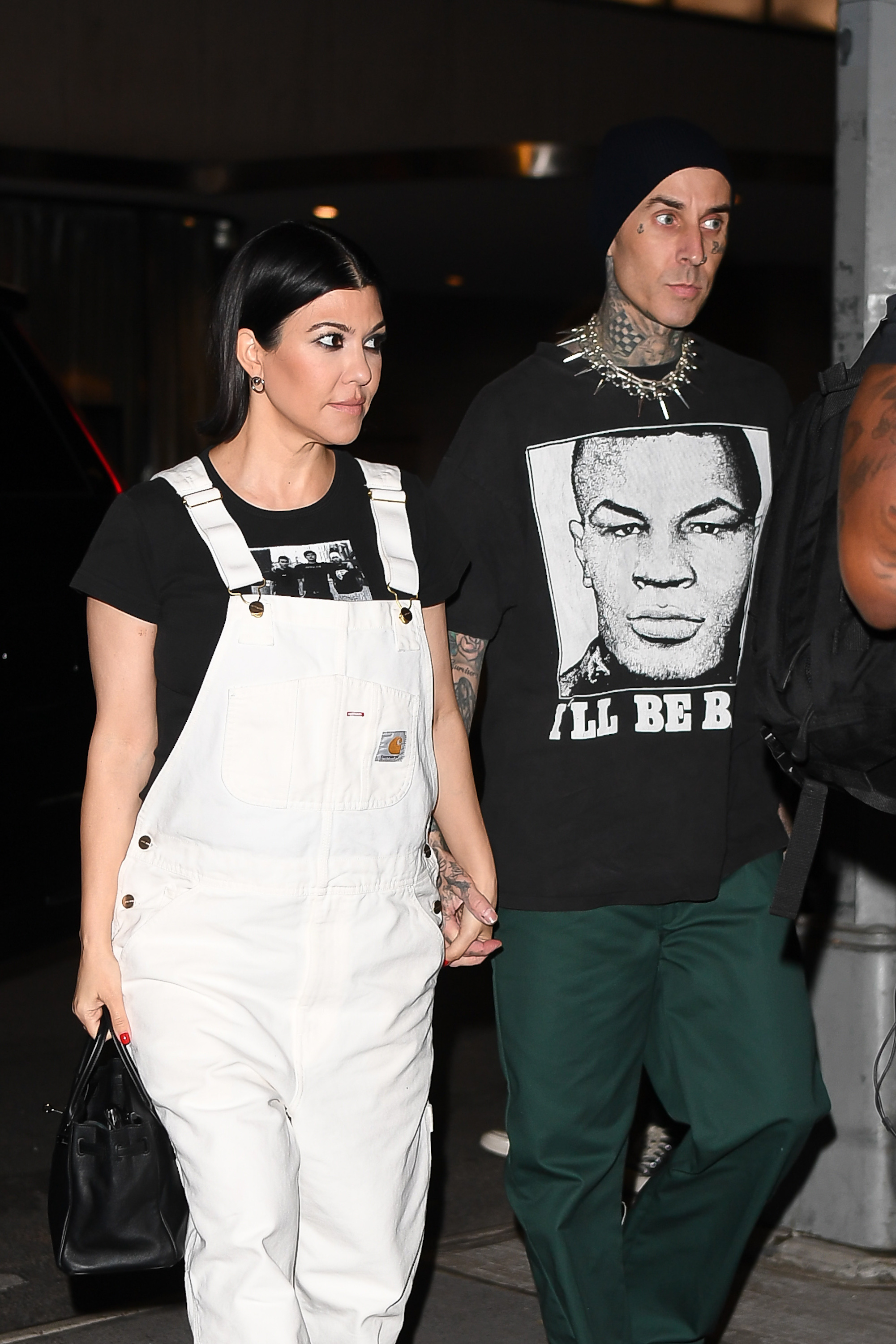 travis and kourtney holding hands as they walk somewhere at night