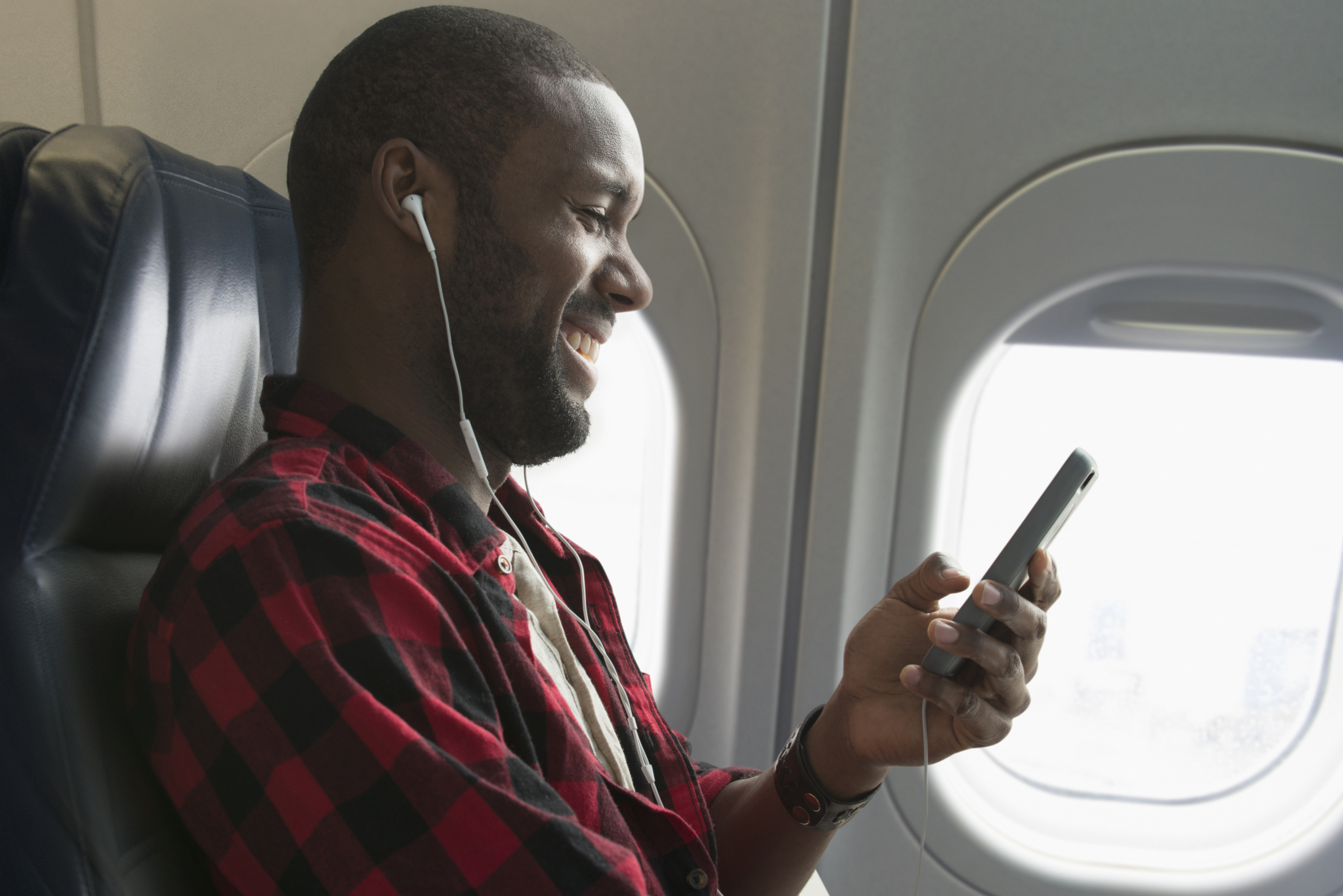 man smiling while on phone on airplane