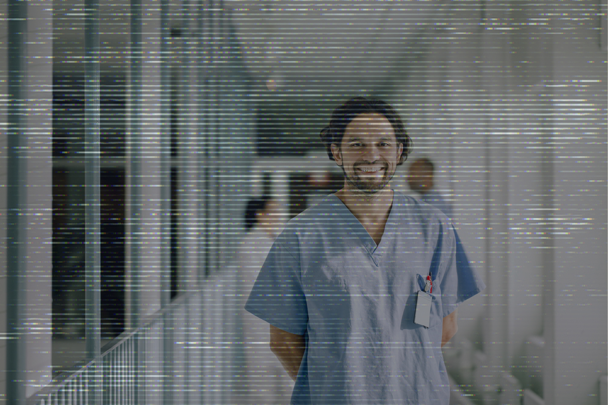 A person in hospital scrubs standing in a hallway and smiling