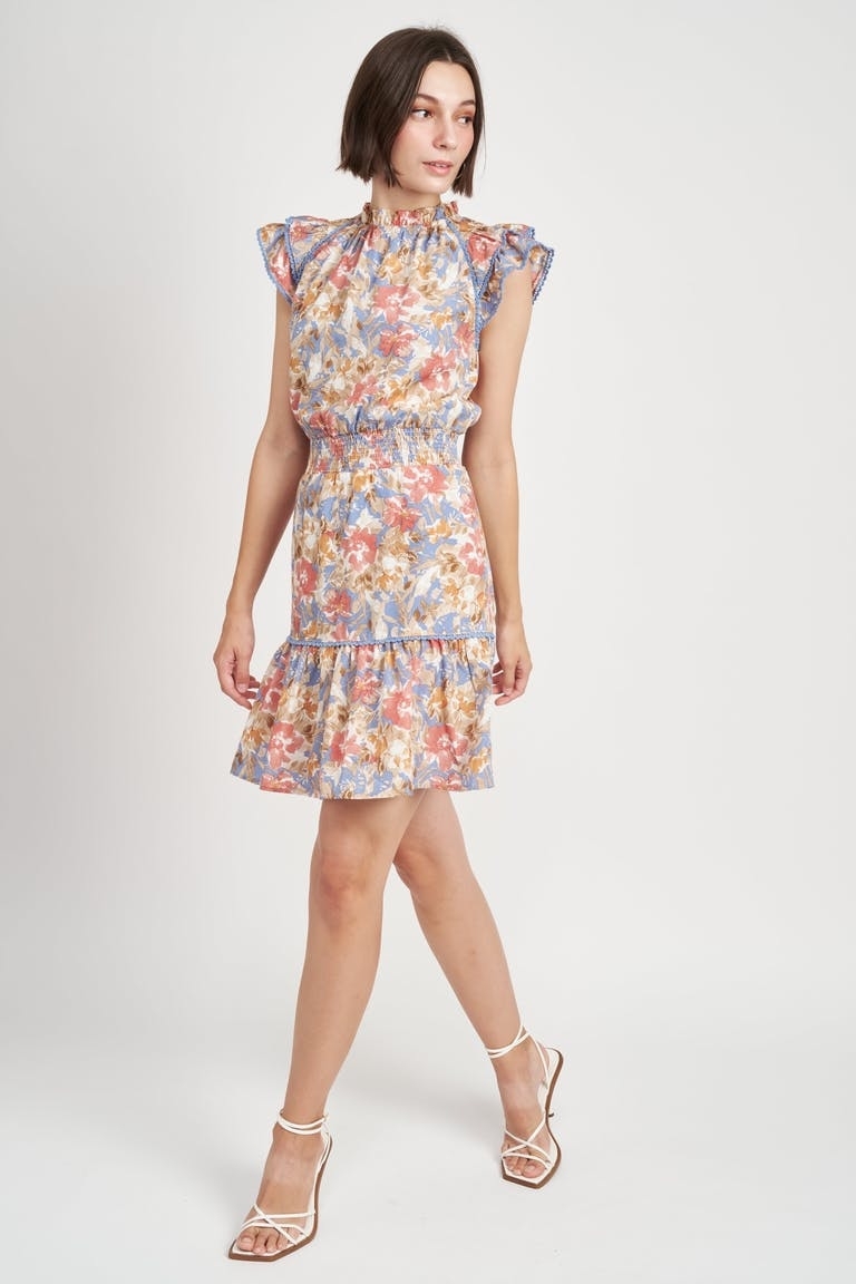 model in elastic waist light blue, pink, and yellow floral mini dress with a high neck and short flutter sleeves