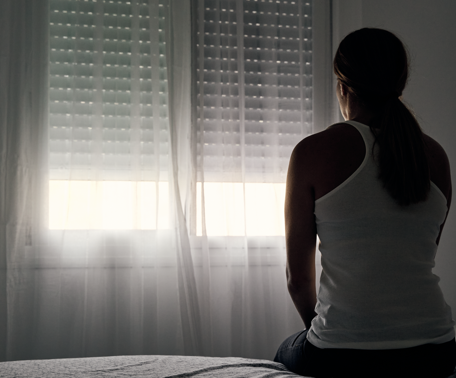 woman sitting on a bed in a dark room