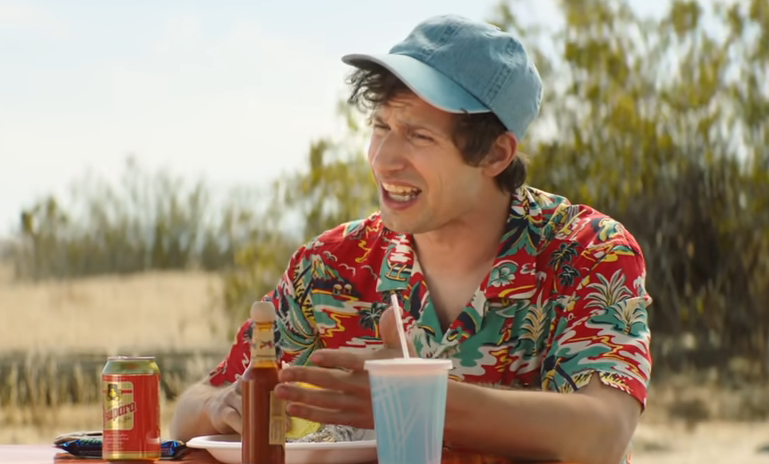 man in an island shirt eating outside