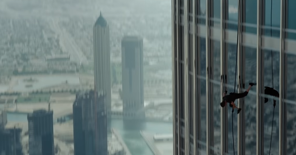 man scaling a glass building