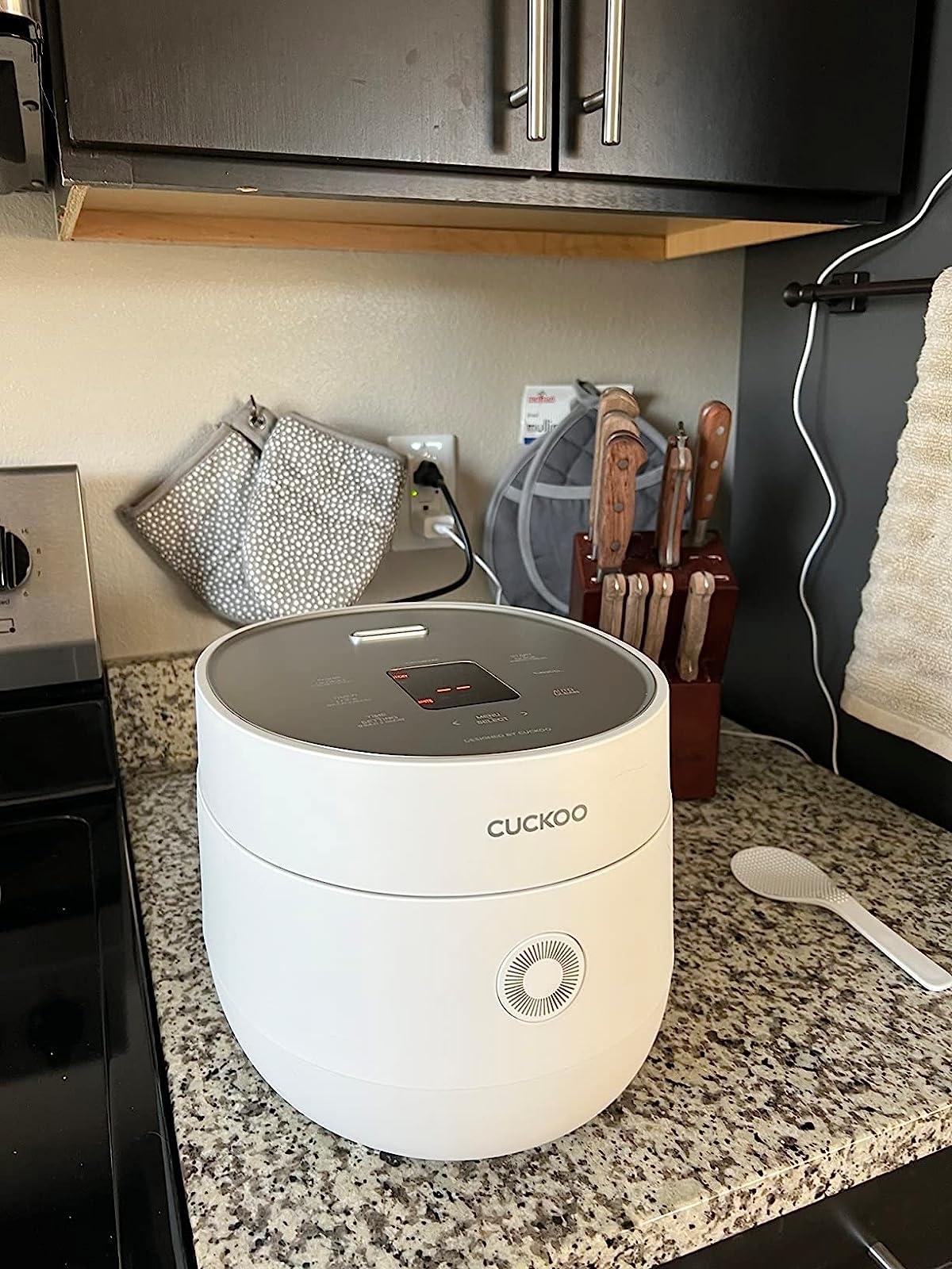 the rice cooker in white on a reviewer's countertop