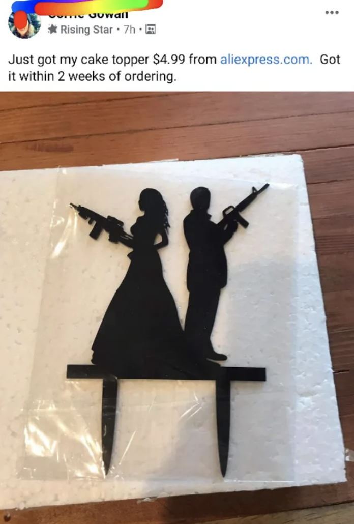 A cake topper where the bride and groom hold guns