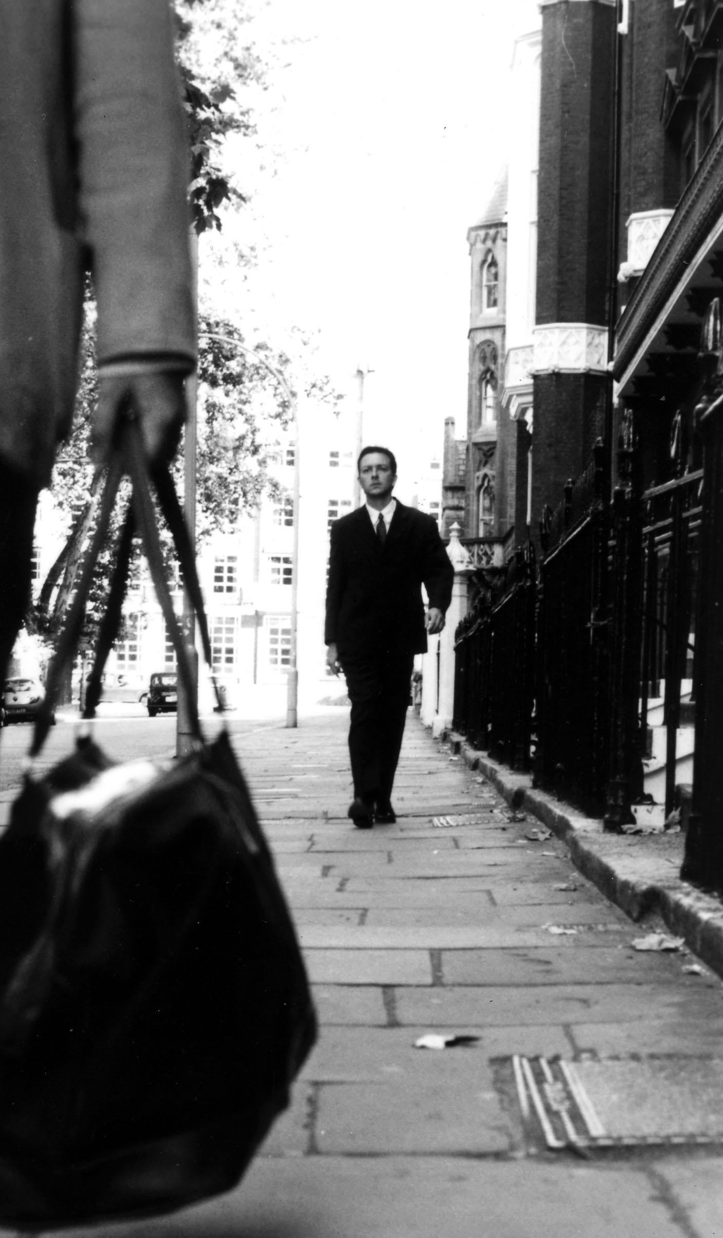 A lone figure walks down the street in the center of an image from the movie Following.