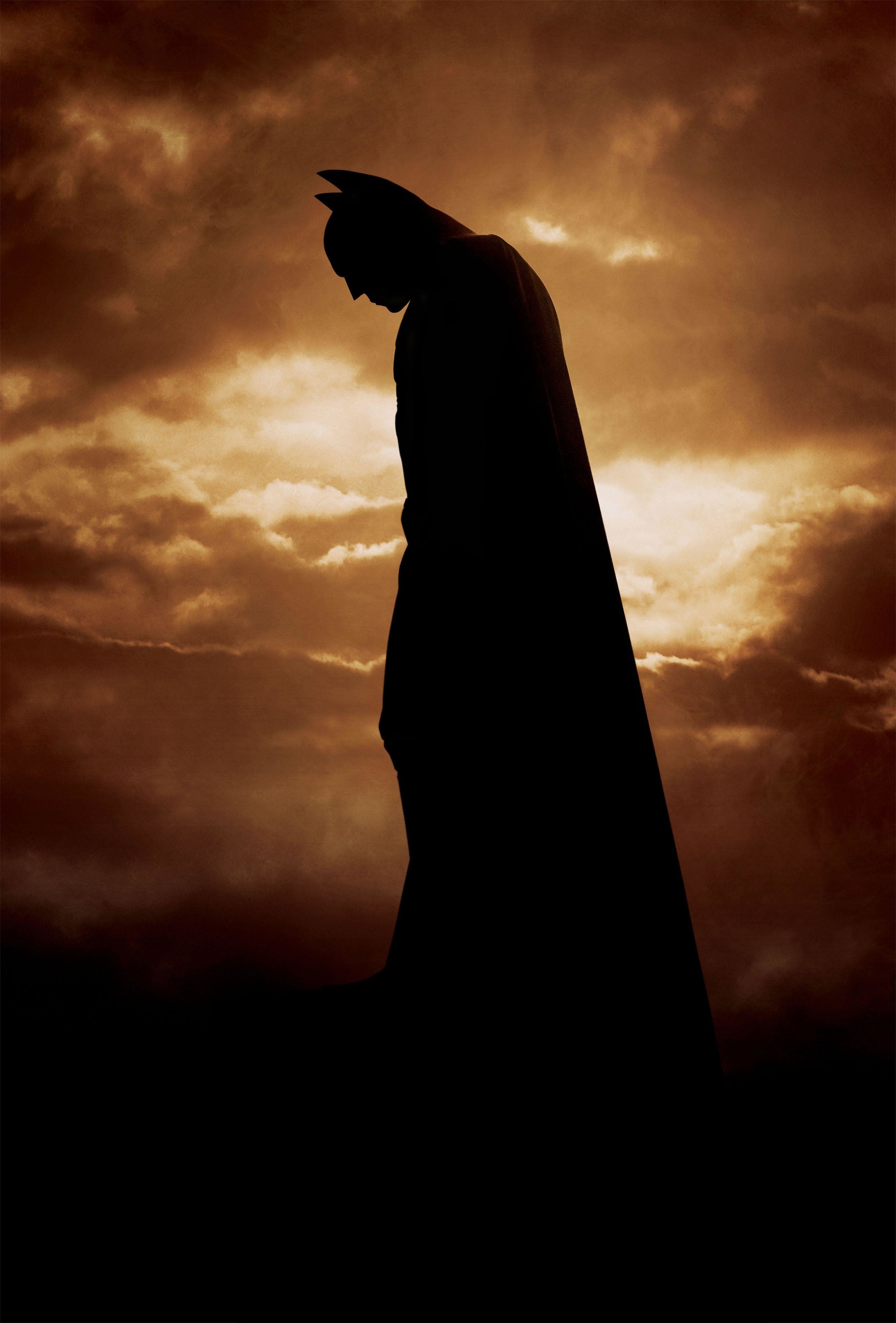 A silhouette of Batman stands in the center of the Batman Begins movie poster.