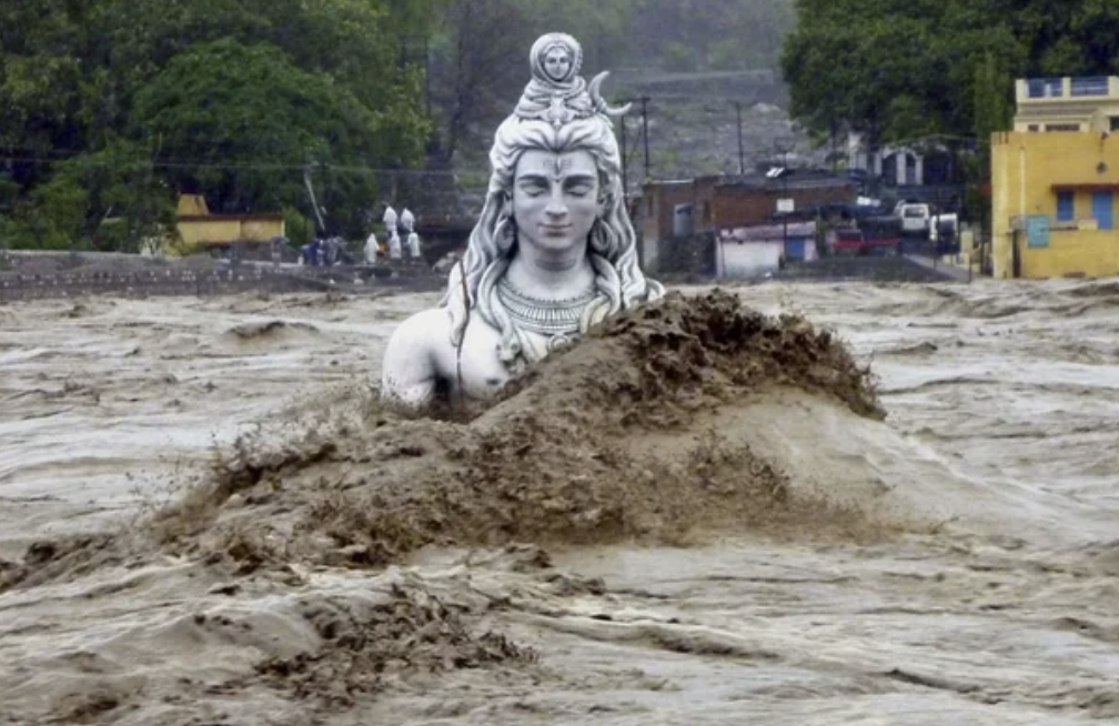The shoulders and face of a smiling statue emerging from muddy water