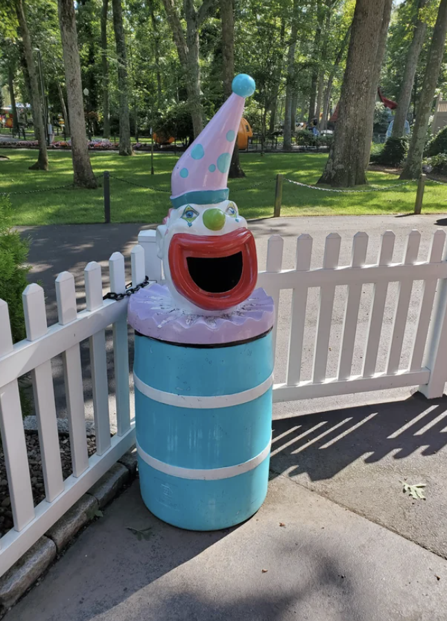 A trash can with a hole in the shape of a clown&#x27;s large red mouth