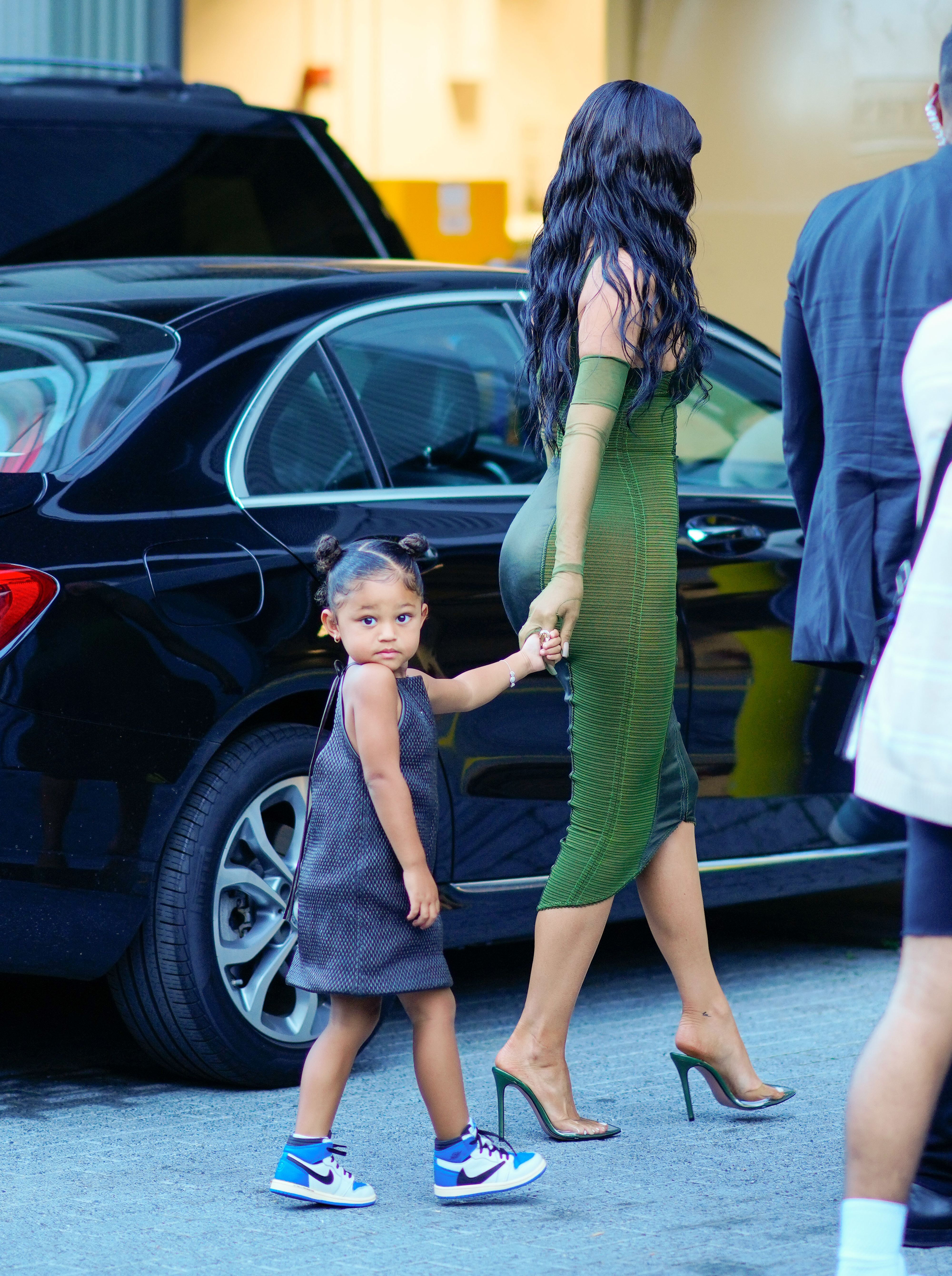 Close-up of Kylie and Stormi walking by a car