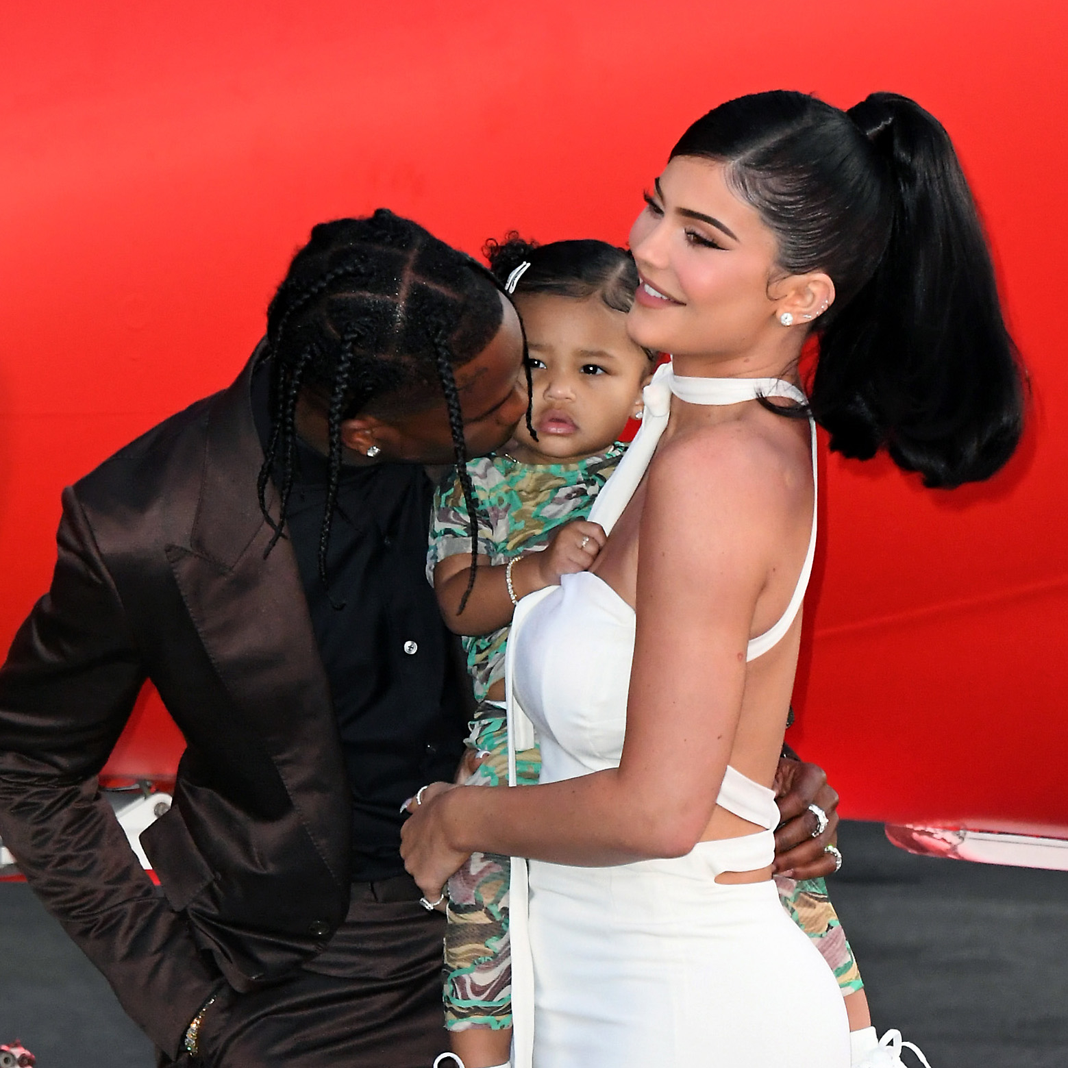Close-up of Kylie holding Stormi, who is being kissed by her father, Travis Scott