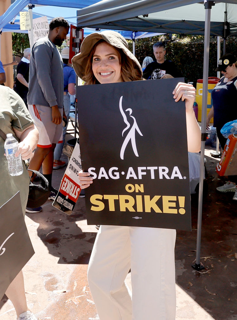 Mandy smiling holding up a sign on the picket line