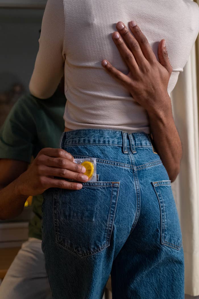 Man slipping a condom in woman&#x27;s back jean pocket