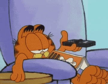 garfield, looking bored, laying on couch and pressing remote control button repeatedly