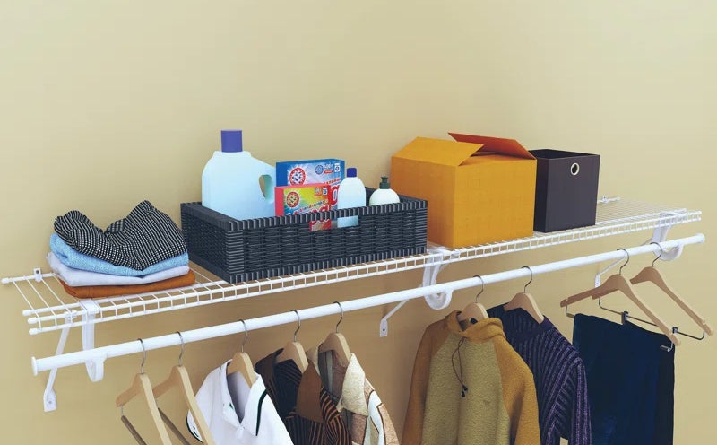 household items on the shelf and clothes hanging on the rod mounted on a wall