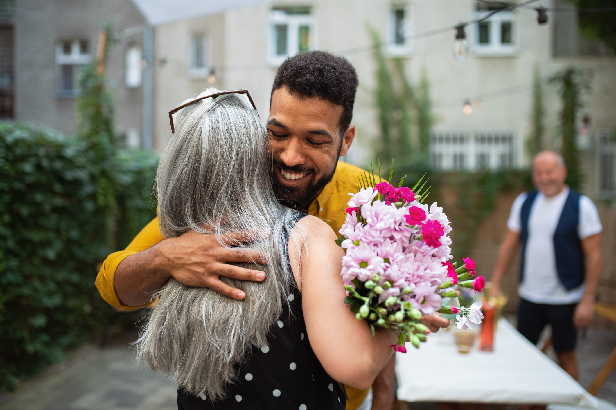 younger man hugging a woman and giving her flowers