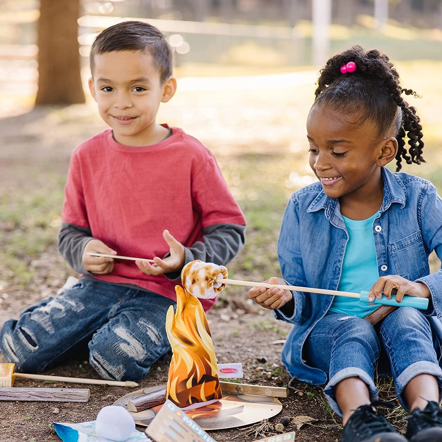 Two kid models play with campfire set