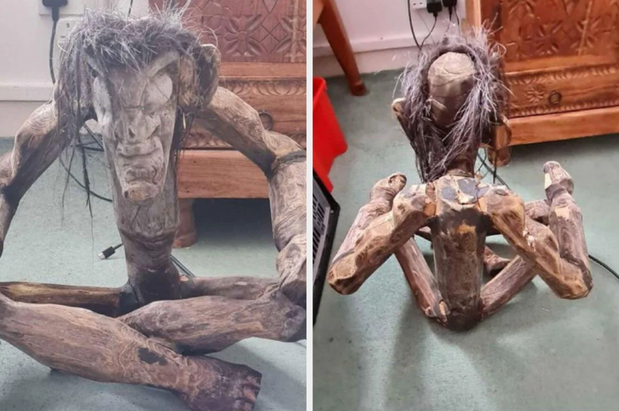 A scary folk art  wooden figure sitting with crossed legs and matted hair