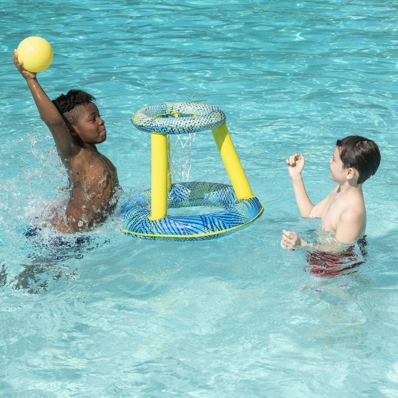 Kids play basketball in a pool