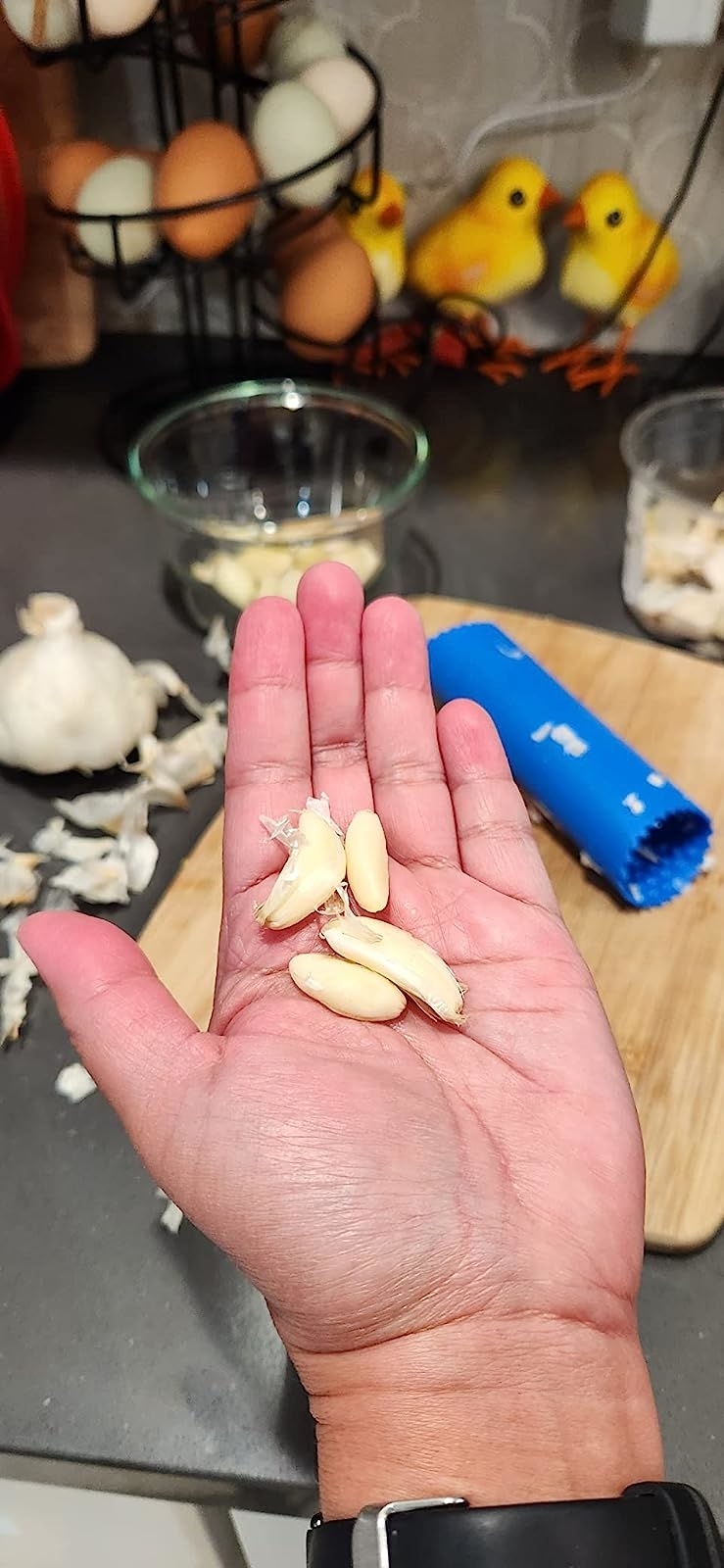 Reviewer&#x27;s photo of them holding four garlic cloves peeled using the garlic roller