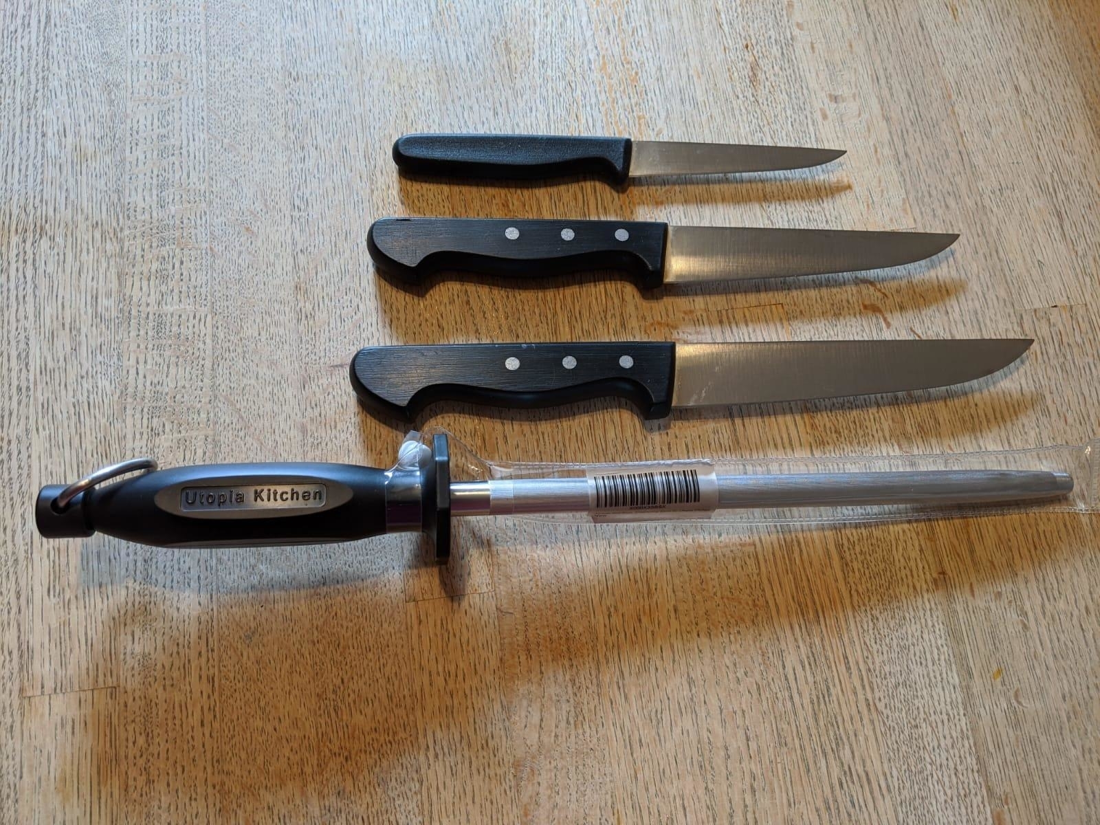 Reviewer&#x27;s photo of the honing steel in the color Black posed alongside three knives