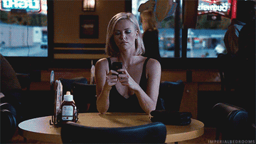 A woman sitting at a table in a restaurant texting