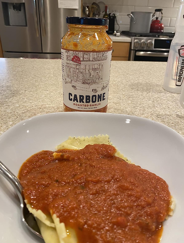 a reviewer&#x27;s photo of the Carbone roasted garlic sauce poured over pasta