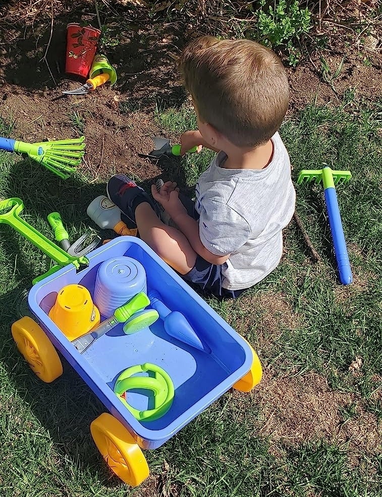 Child plays with wagon and gardening tools