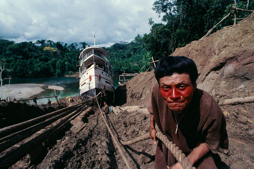 man pulling a rope tied to a large boat