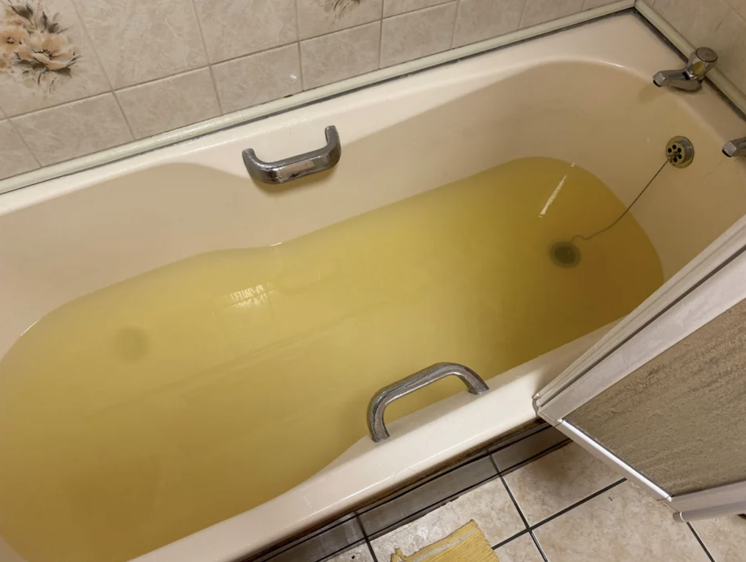 An ankle deep layer of yellow stagnant water is sitting in the bathtub