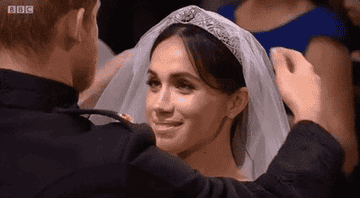 Duchess Meghan Markle looks up at Prince Harry during their wedding as he moves her veil back
