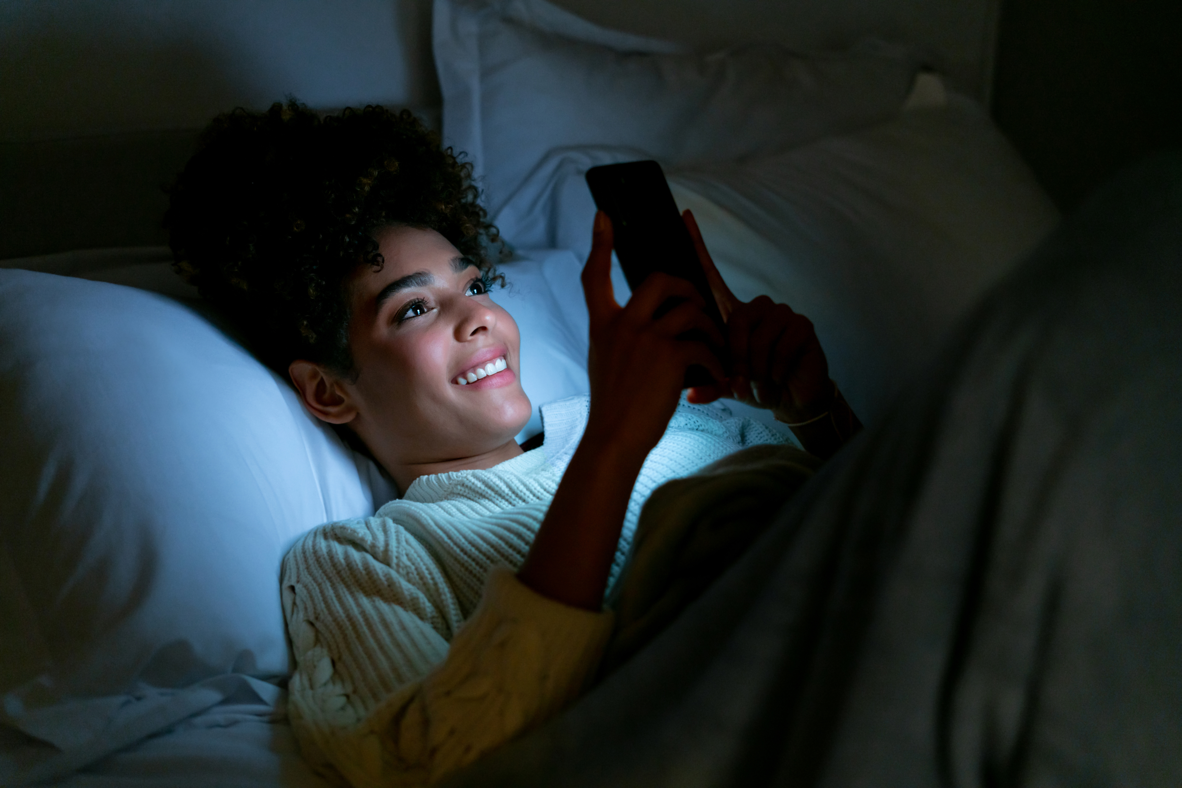 person scrolling on their phone in bed