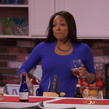 GIF of a woman locking her lips and throwing away the key while holding a glass of wine