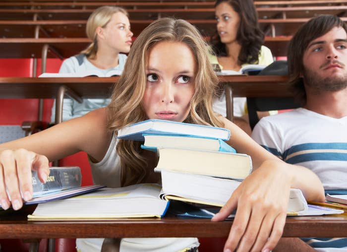 A woman sitting in class leaning on her books