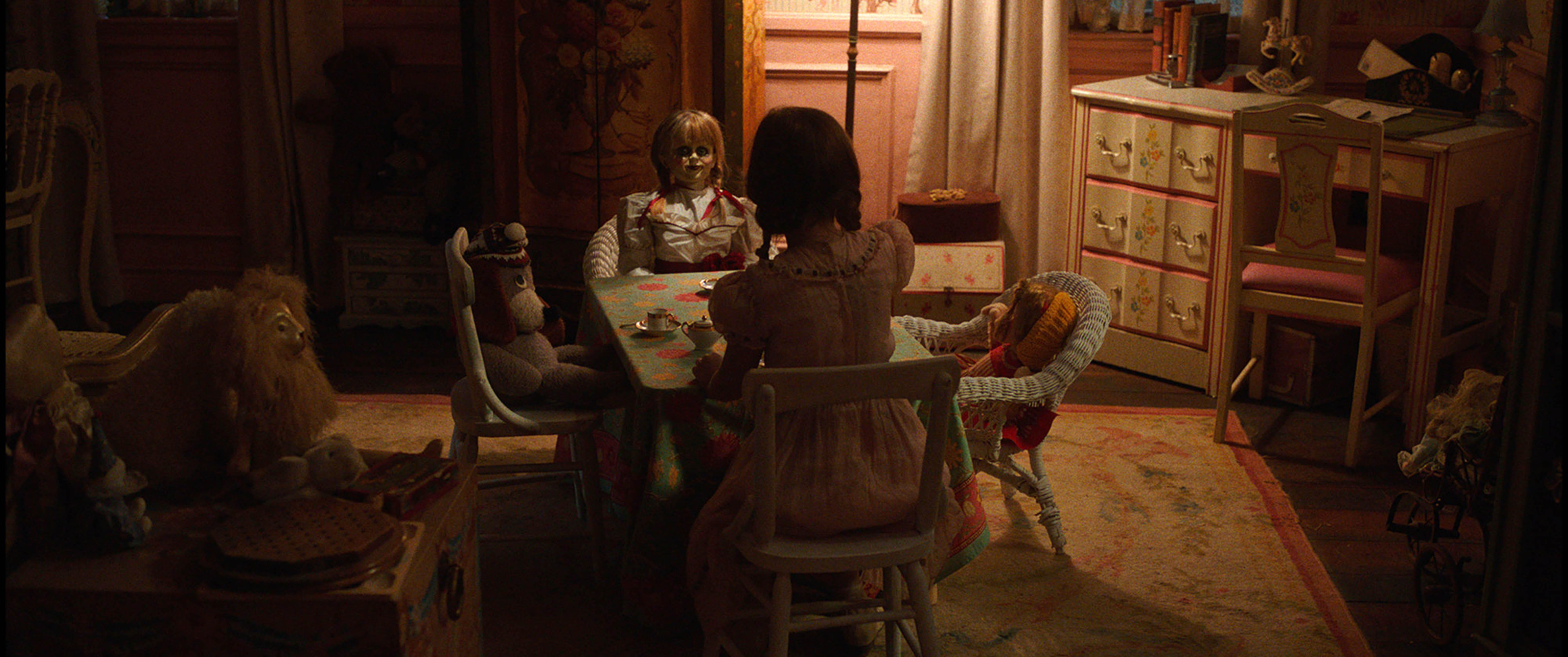 A young girl has a pretend tea party with a terrifying doll