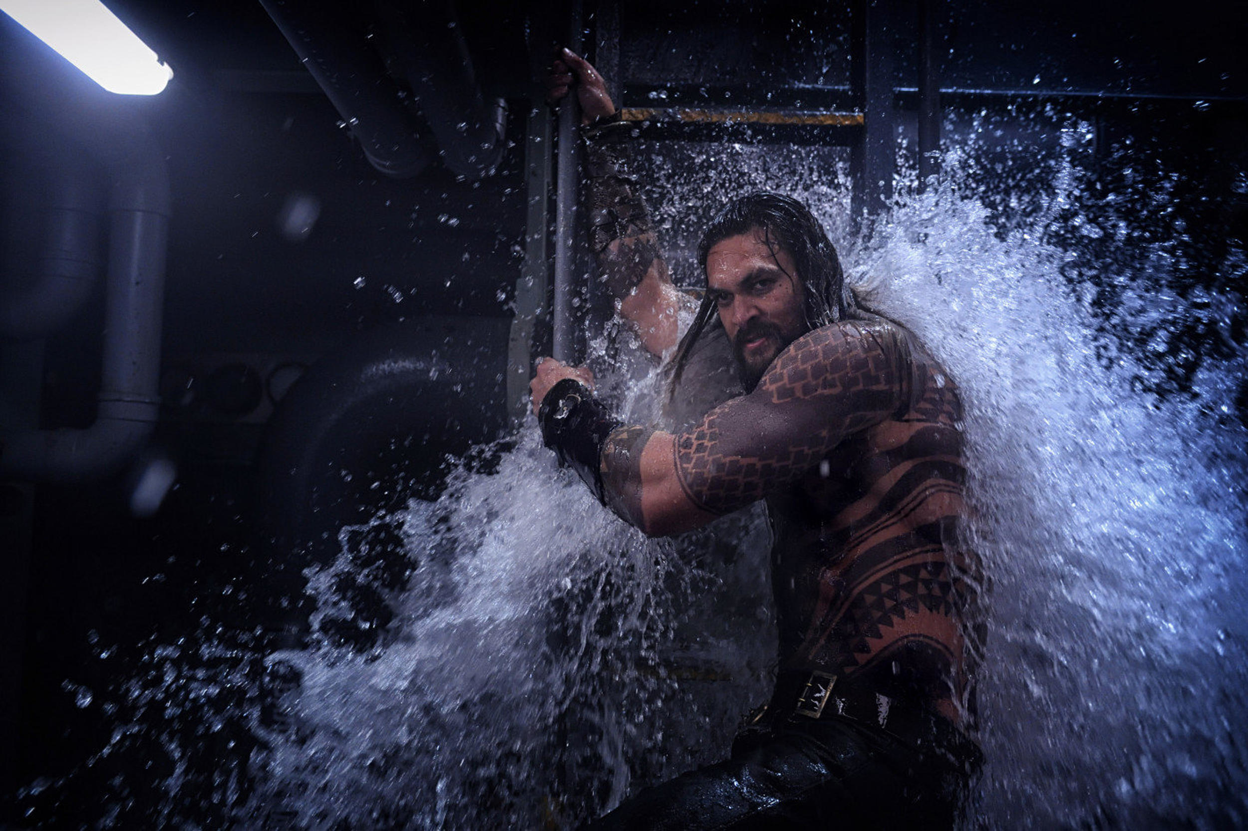 Jason Momoa blocks an incoming wave of water with his body