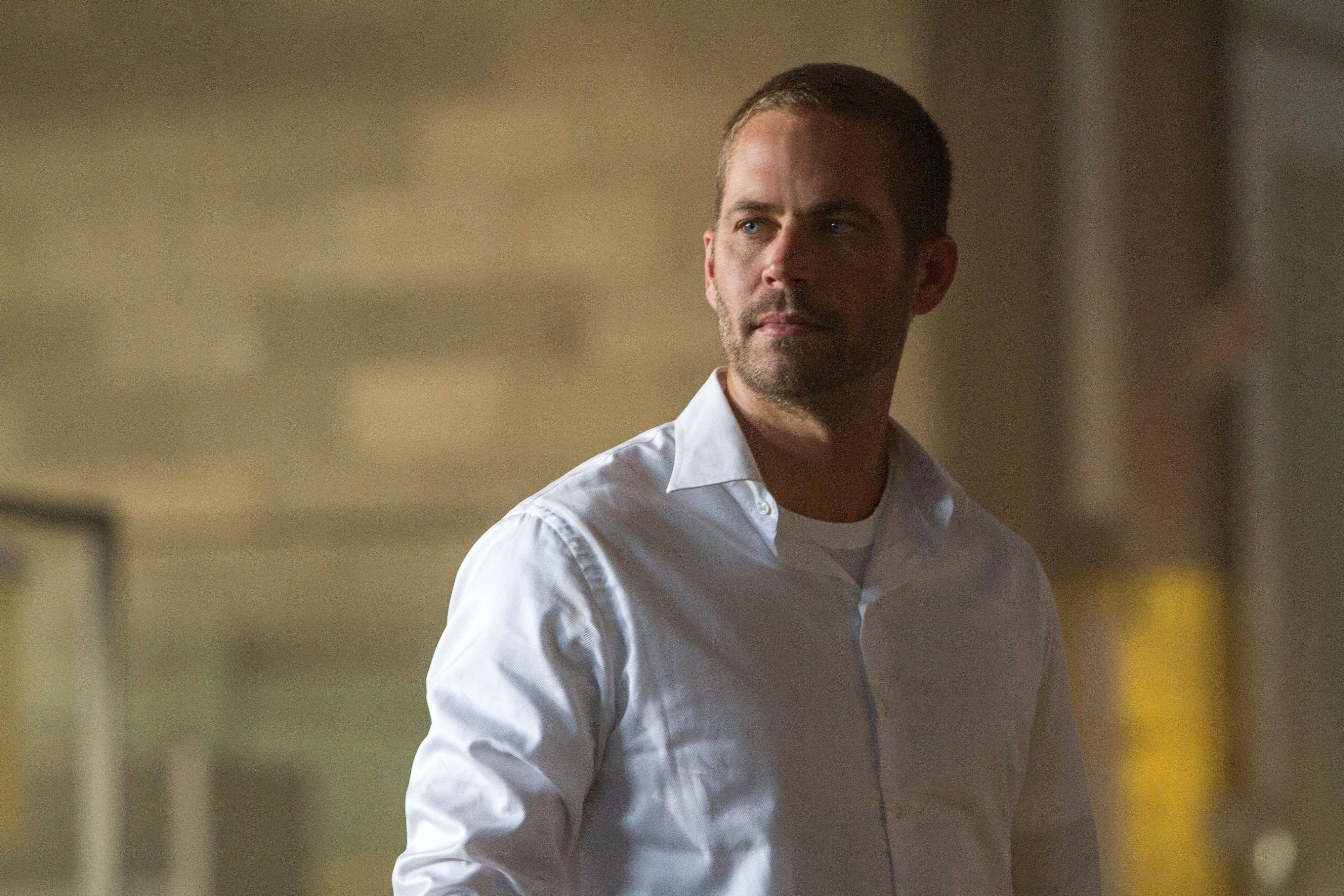 Paul Walker stares off-screen while inside of a building