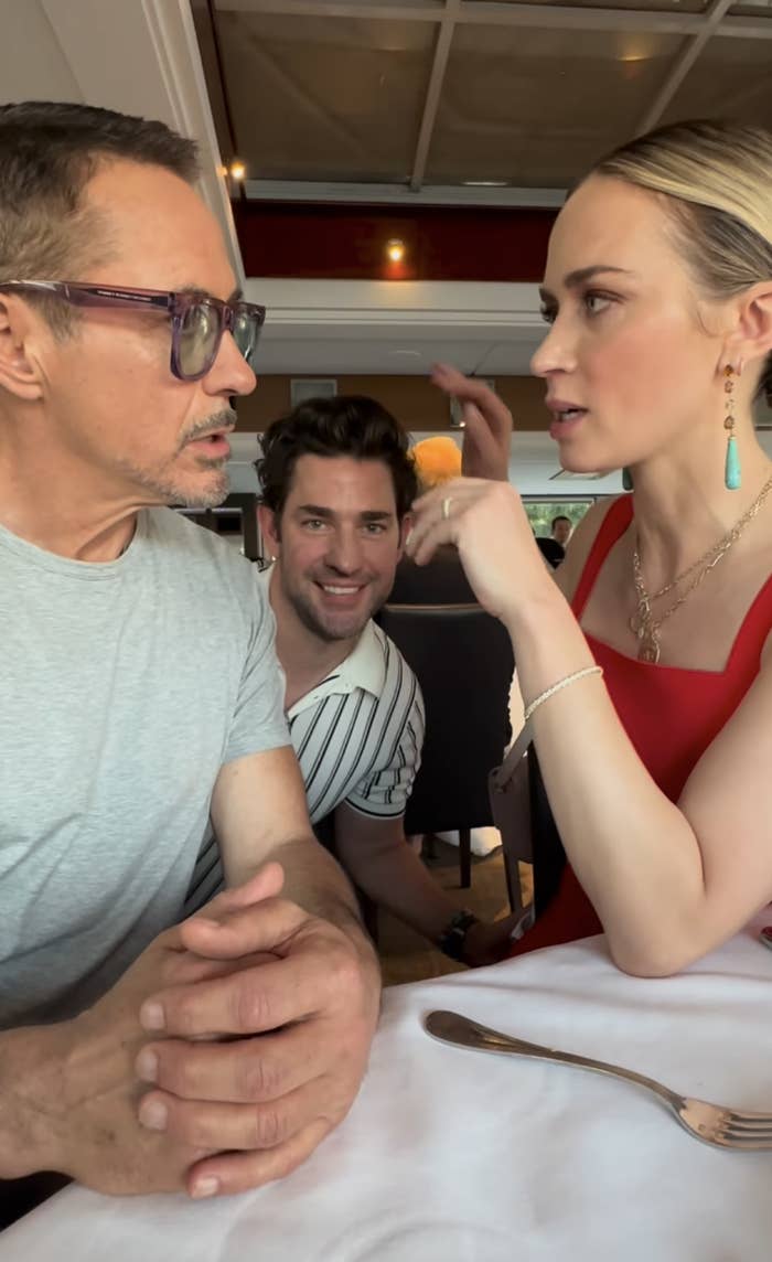 Emily and Robert Downey Jr. having a serious conversation while John smiles awkwardly in the background