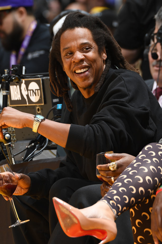 Close-up of Jay-Z smiling and drinking from a wine glass