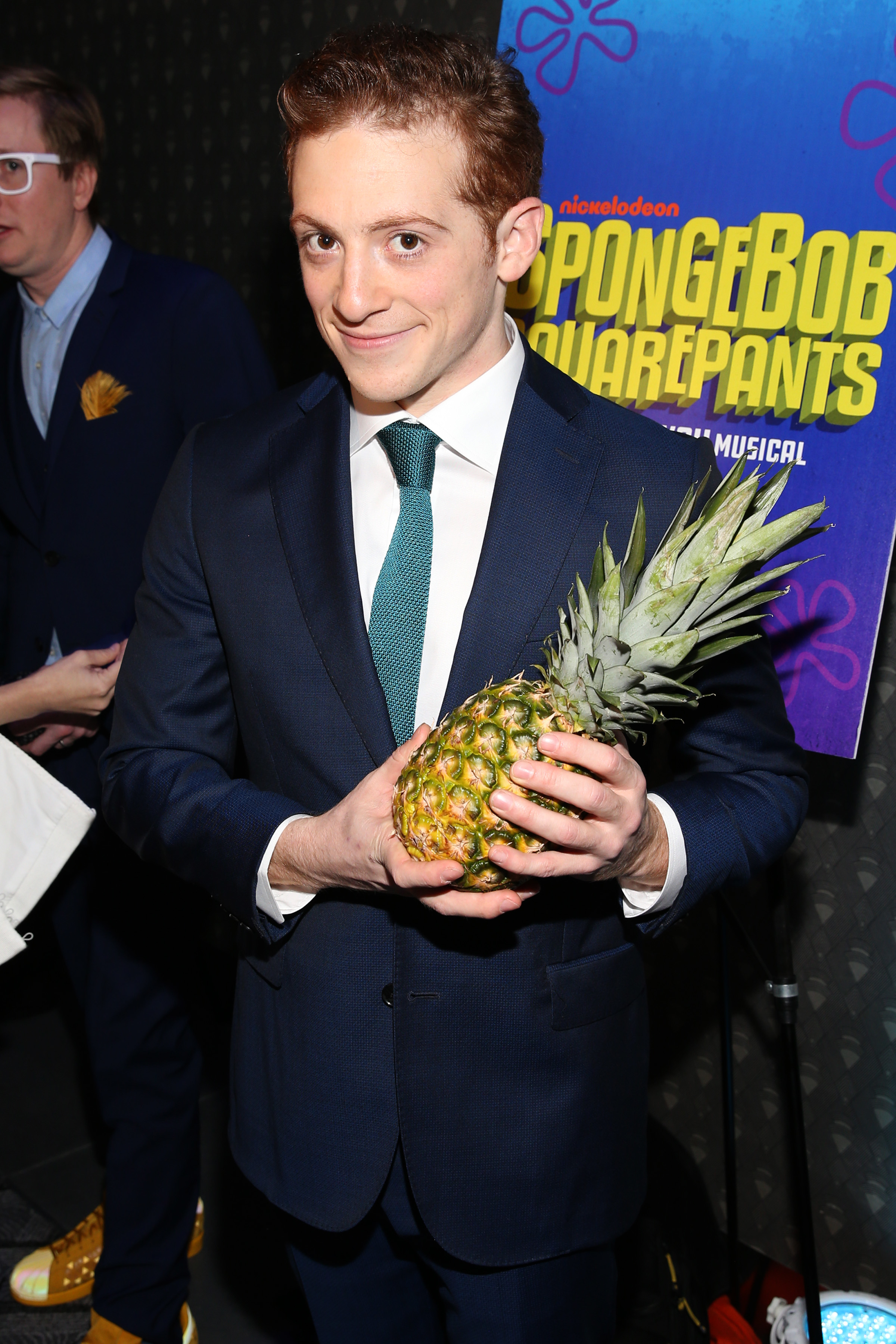 Ethan in a suit and holding a pineapple
