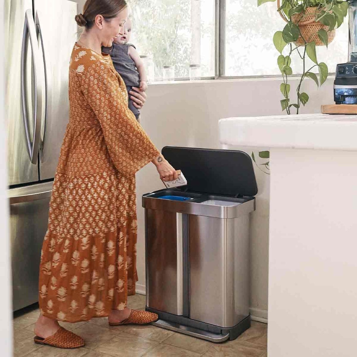 a stainless steel garbage can with two sections, one for recyclables and one for garbage