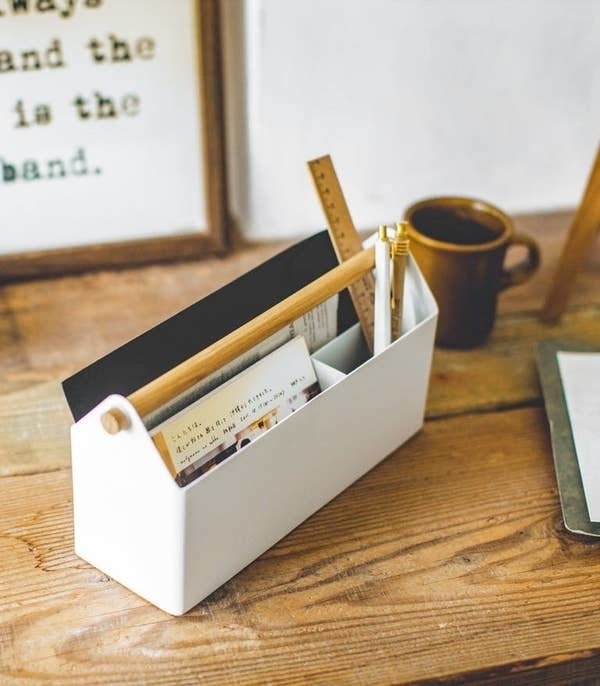 white metal and wood slim desk organizer with papers, rulers, and pens insisde
