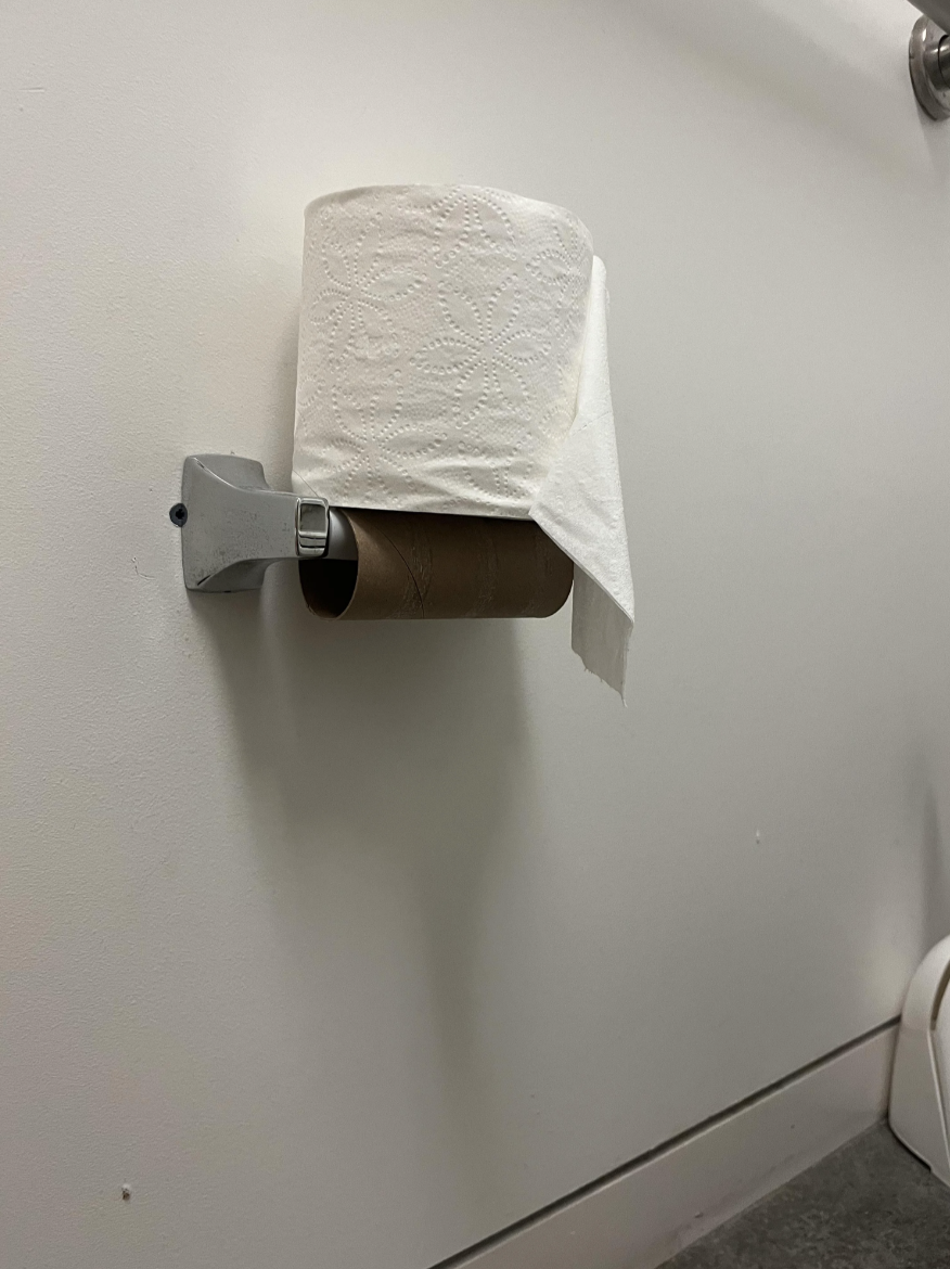 The toilet paper has simply been placed on top of the holder instead of actually being installed
