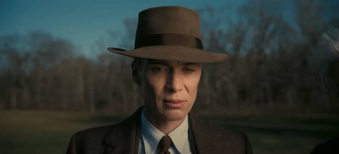 Cillian Murphy as J. Robert Oppenheimer wearing his signature hat while standing outside